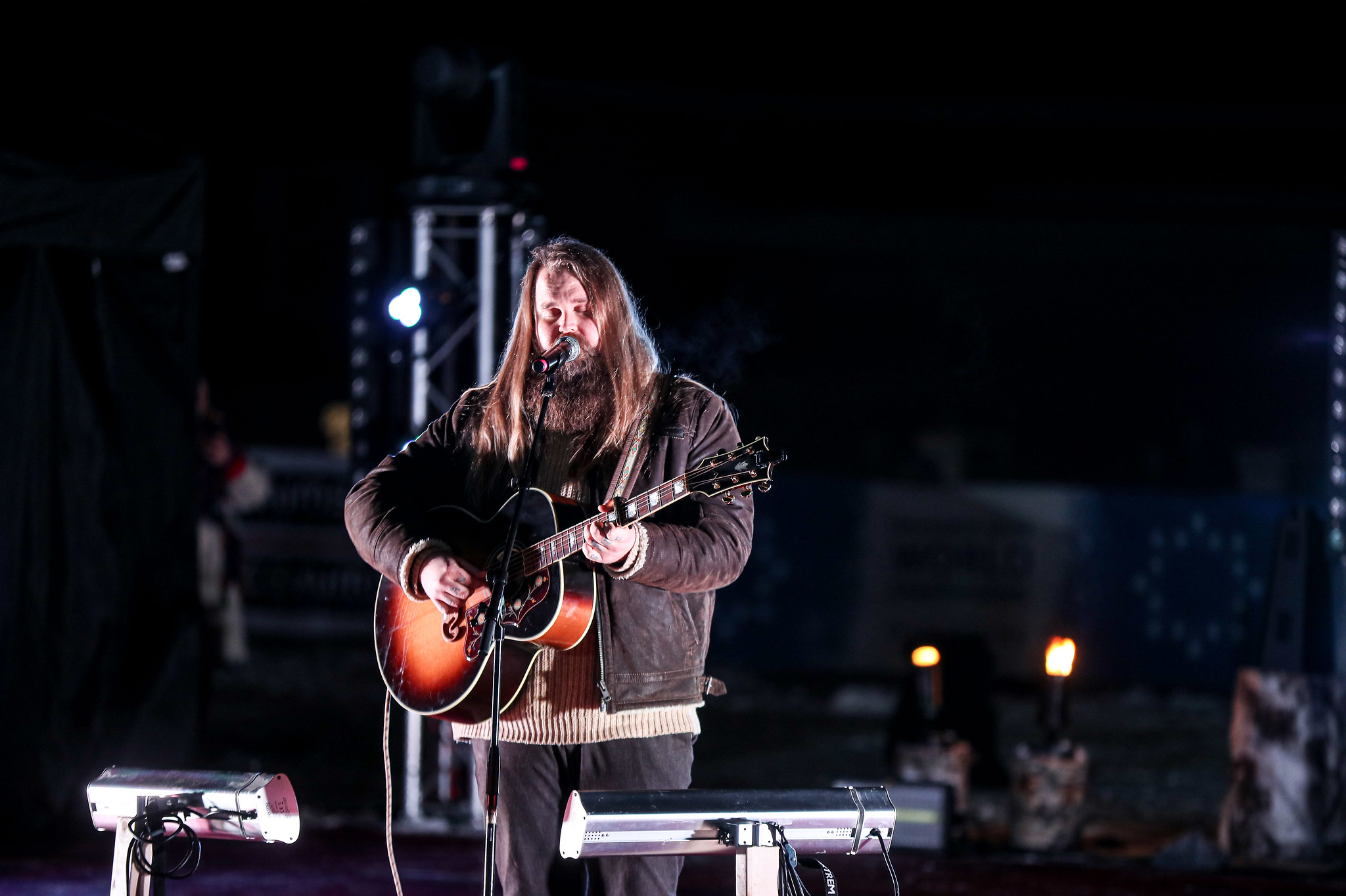 En man står och sjunger med sin gitarr på en scen.